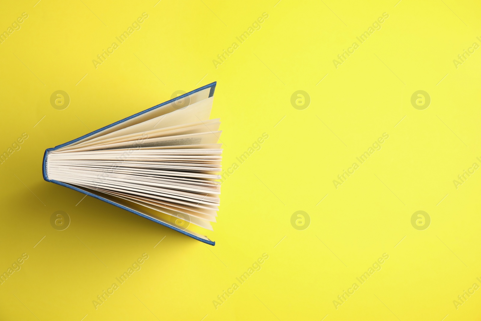 Photo of Hardcover book on yellow background, top view. Space for text
