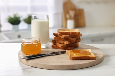 Photo of Breakfast served in kitchen. Crunchy toasts, honey and milk on white table