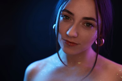 Portrait of beautiful woman on dark background in neon lights