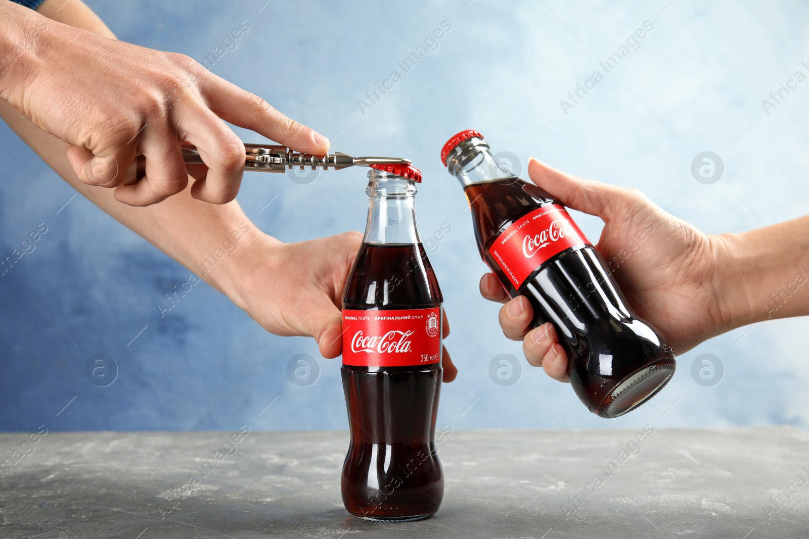 Photo of MYKOLAIV, UKRAINE - NOVEMBER 15, 2018: People with bottles of Coca Cola at table, closeup