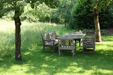 Empty wooden table with bench and chairs in garden