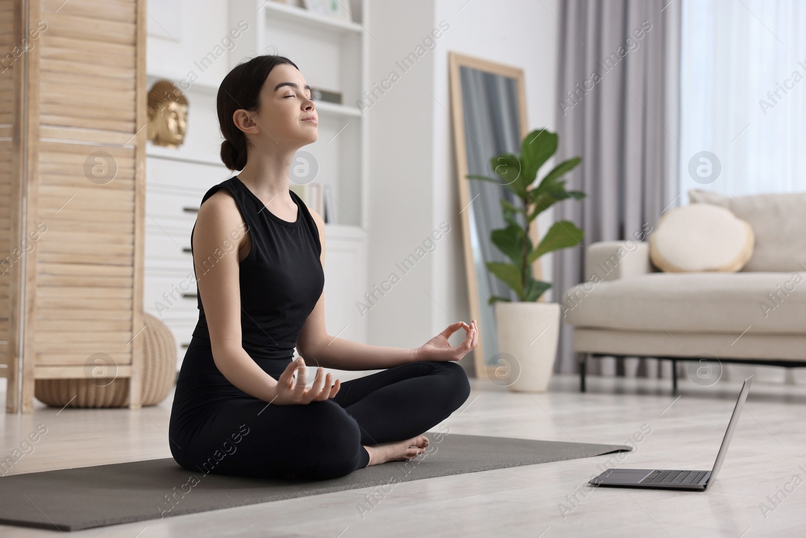 Photo of Beautiful girl having yoga class with online couch at home