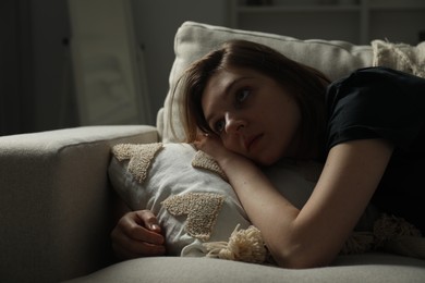 Sad young woman lying on sofa at home