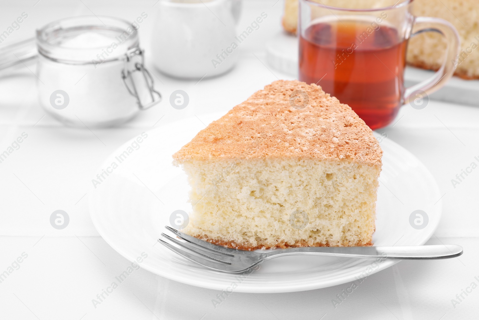 Photo of Piece of tasty sponge cake on white tiled table