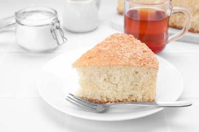 Photo of Piece of tasty sponge cake on white tiled table