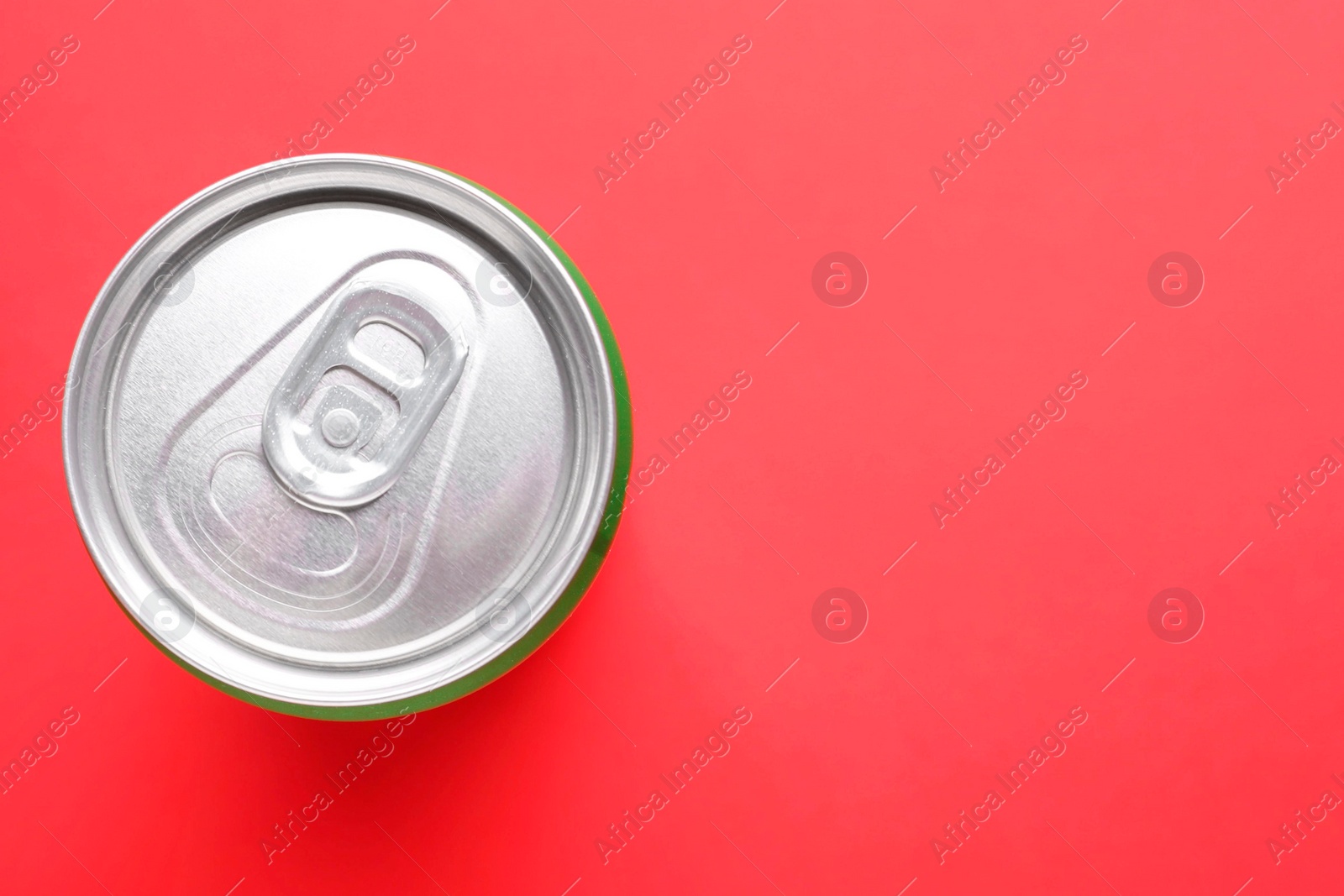 Photo of Energy drink in can on red background, top view. Space for text