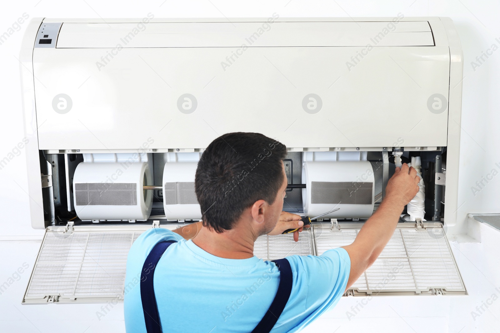 Photo of Technician repairing and checking air conditioner indoors