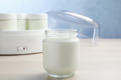 Photo of Glass jar with tasty yogurt on white wooden table