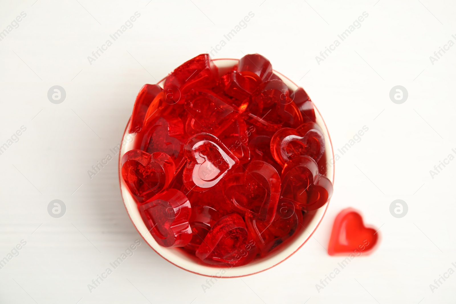 Photo of Tasty heart shaped jelly candies on white table, flat lay
