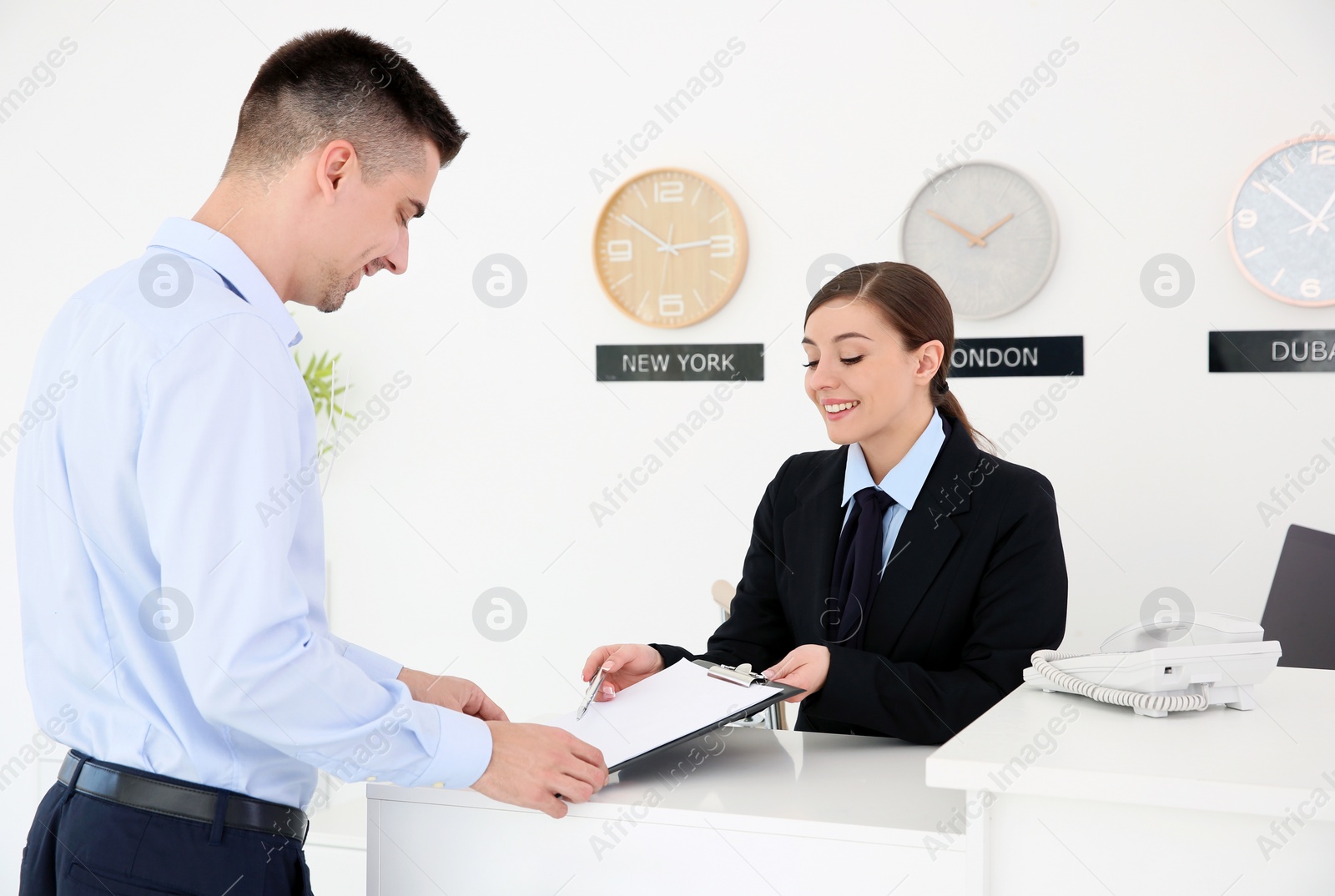 Photo of Young man filling form at reception desk in hotel