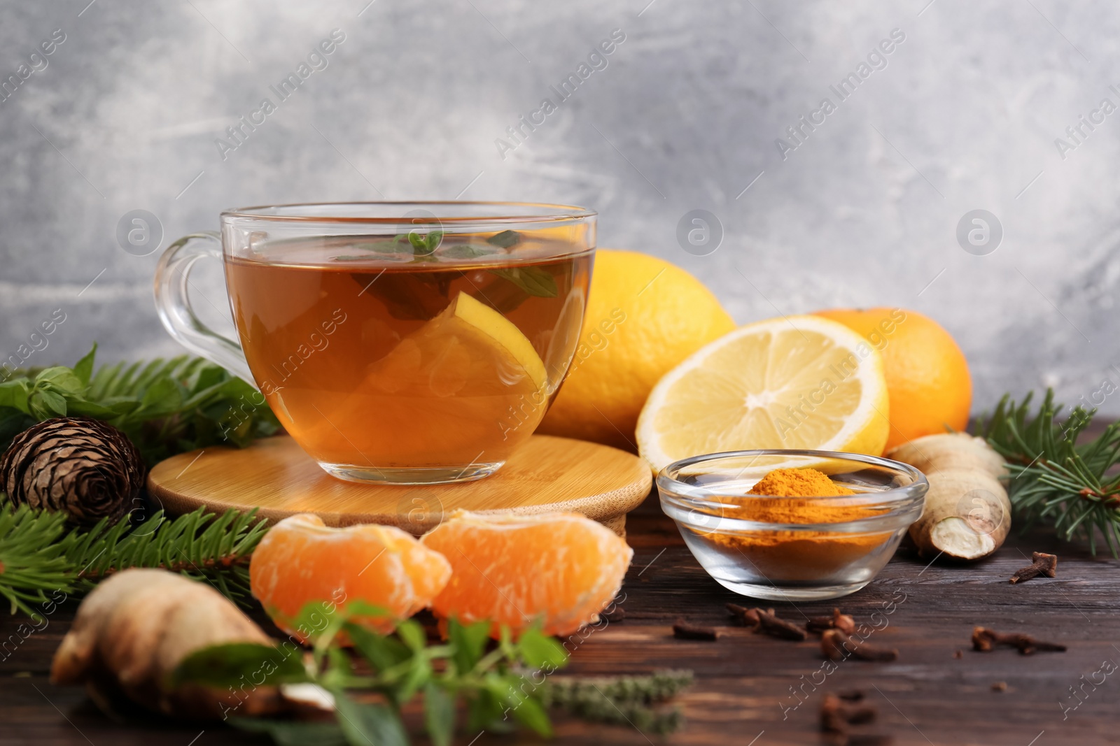 Photo of Glass cup of delicious immunity boosting tea and ingredients on wooden table