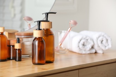 Bottles with dispenser caps and cosmetic products on wooden table indoors