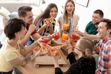 Young people having fun party with delicious pizza indoors