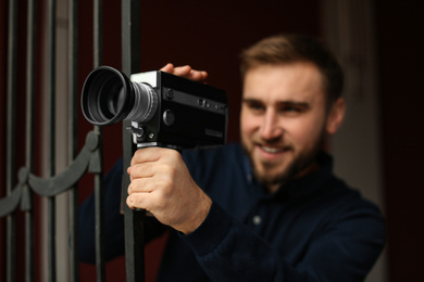 Photo of Young man with vintage video camera outdoors, focus on lens