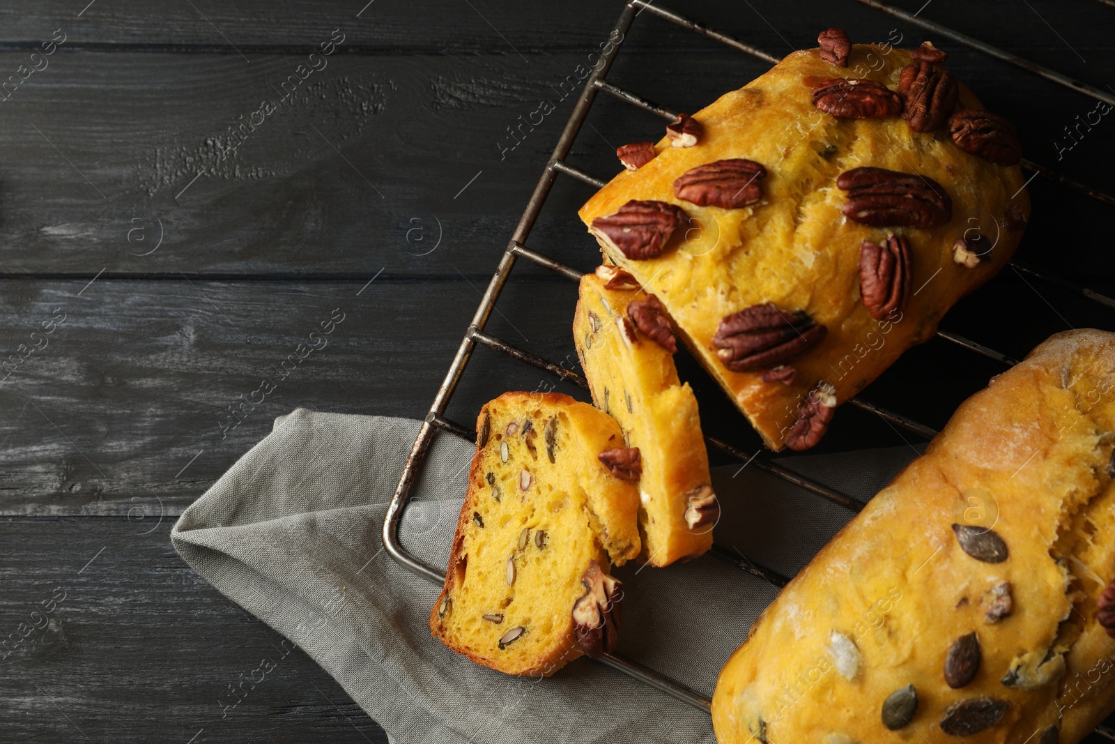 Photo of Delicious pumpkin bread with pecan nuts on black wooden table, flat lay. Space for text