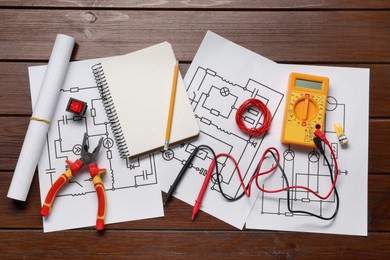 Photo of Flat lay composition with wiring diagrams and digital multimeter on wooden table