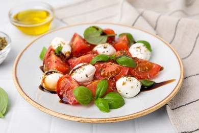 Tasty salad Caprese with mozarella balls, tomatoes, basil and sauce on white tiled table, closeup