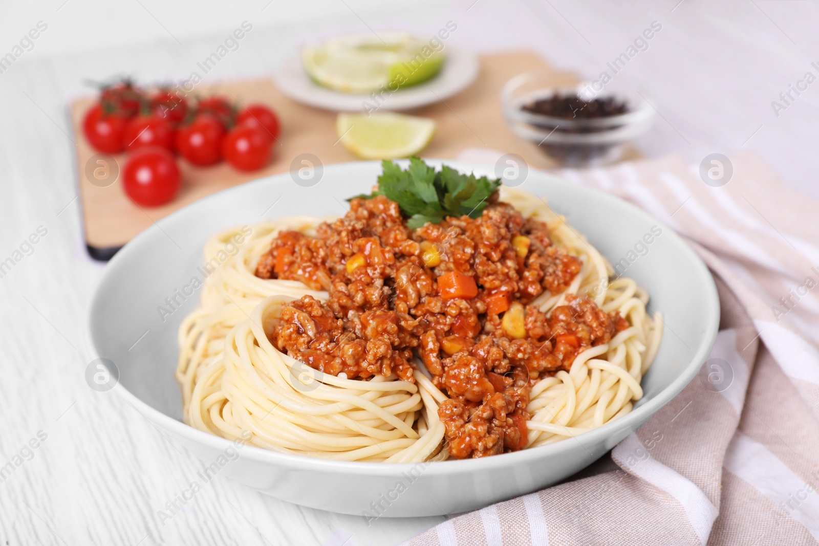 Photo of Tasty dish with fried minced meat, spaghetti, carrot and corn on white wooden table, closeup