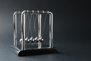 Photo of Newton's cradle on dark background, space for text. Physics law of energy conservation