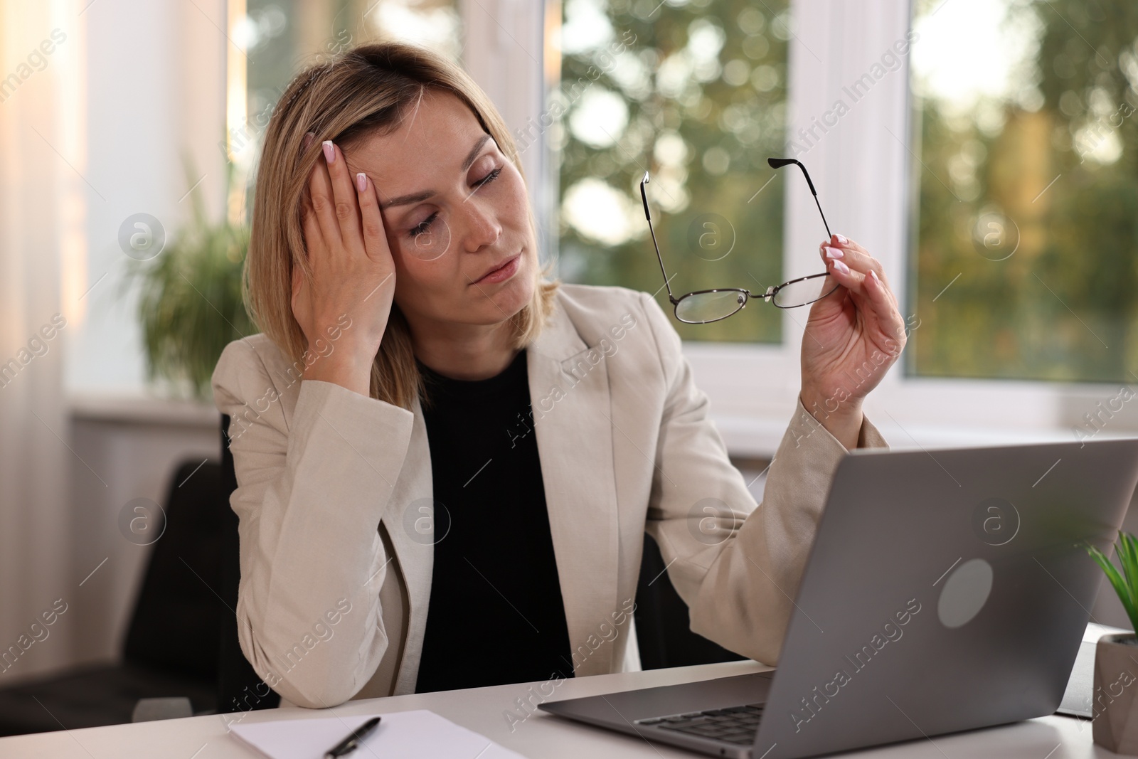 Photo of Overwhelmed woman sitting at table in office