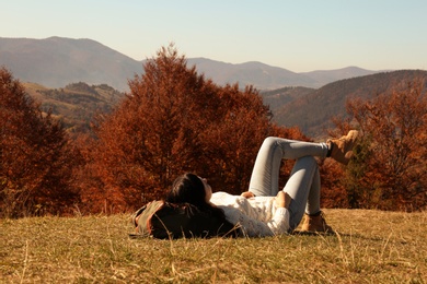 Woman in warm clothes relaxing on mountain slope