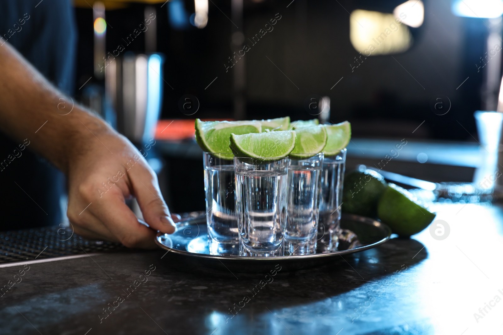 Photo of Bartender with shot glasses of Mexican Tequila at bar counter, closeup