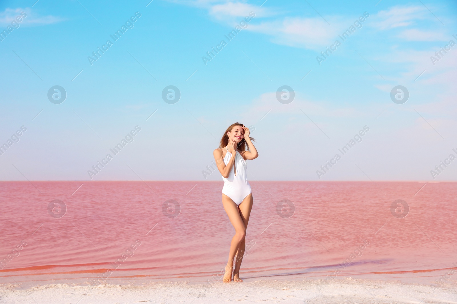 Photo of Beautiful woman in swimsuit posing near pink lake on sunny day