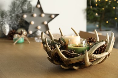 Photo of Burning scented conifer candles with Christmas decor  on wooden table indoors