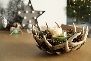 Burning scented conifer candles with Christmas decor  on wooden table indoors