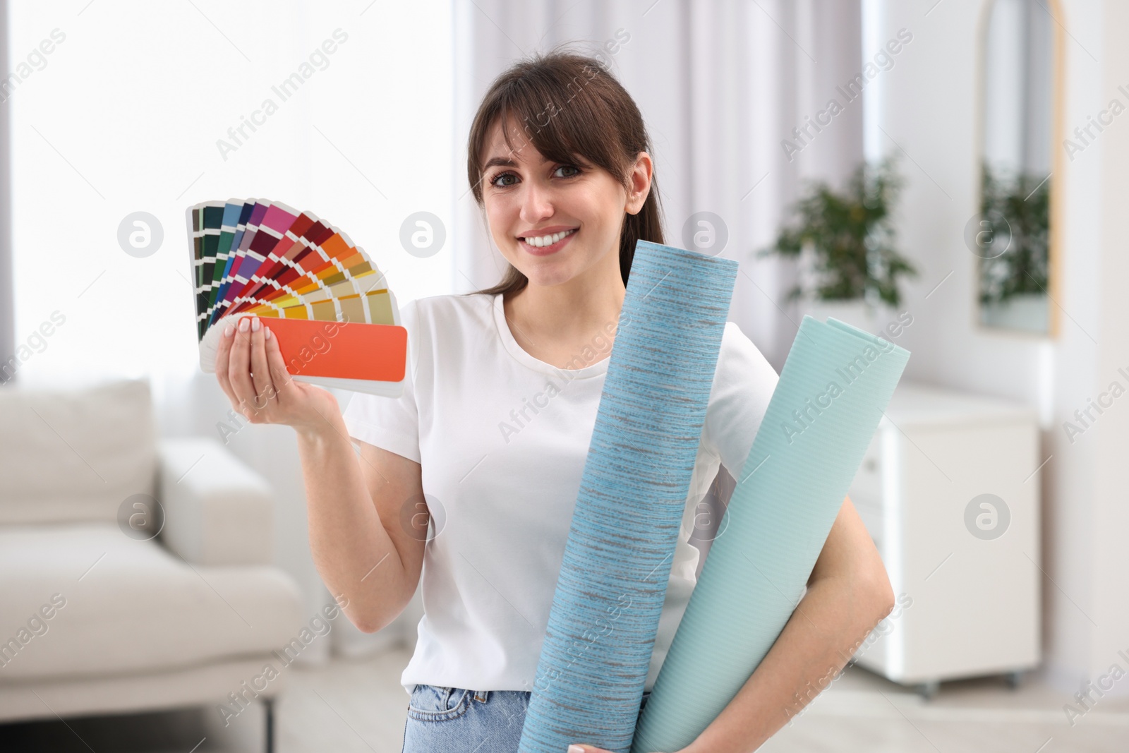 Photo of Woman with wallpaper rolls and color palette in room