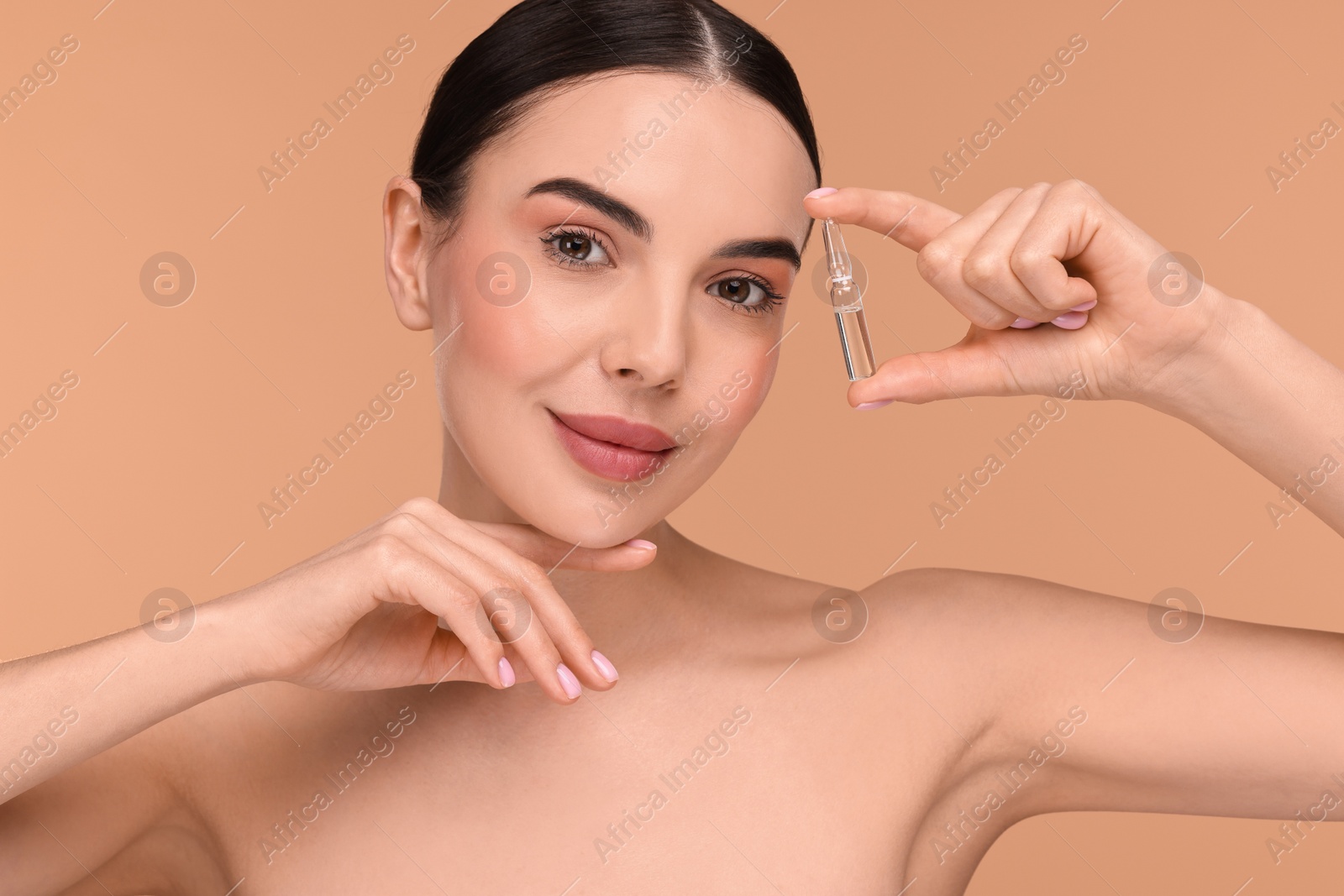 Photo of Beautiful young woman holding skincare ampoule on beige background