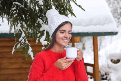 Happy beautiful woman with mulled wine outdoors on snowy day 