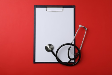 Clipboard with space for text and stethoscope on color background, top view. Medical objects