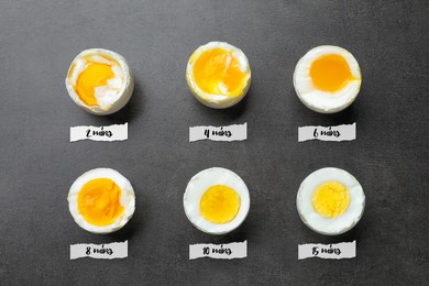 Different readiness stages of boiled chicken eggs on dark grey table, flat lay