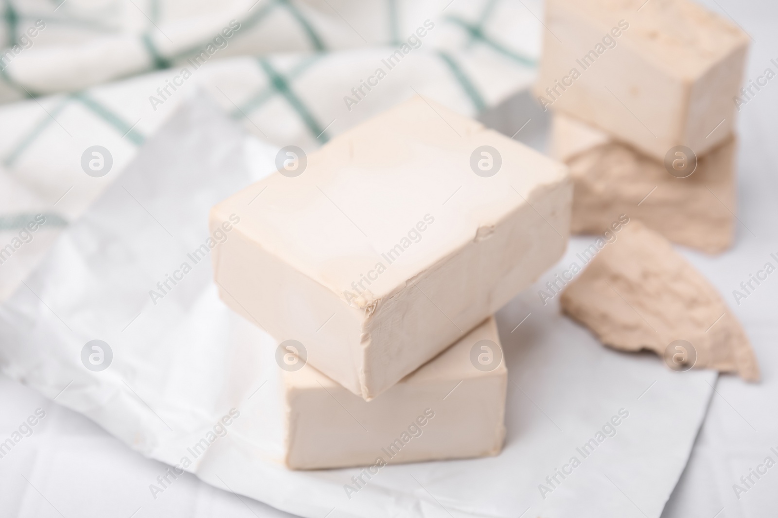 Photo of Blocks of compressed yeast on white table, closeup