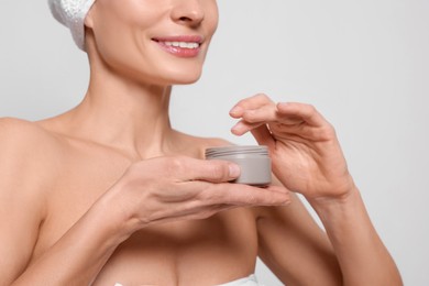 Woman with jar of body cream on white background, closeup