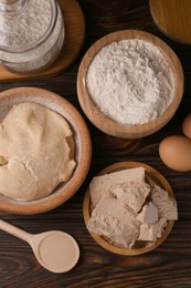 Photo of Different types of yeast, eggs, flour and dough on wooden table, flat lay