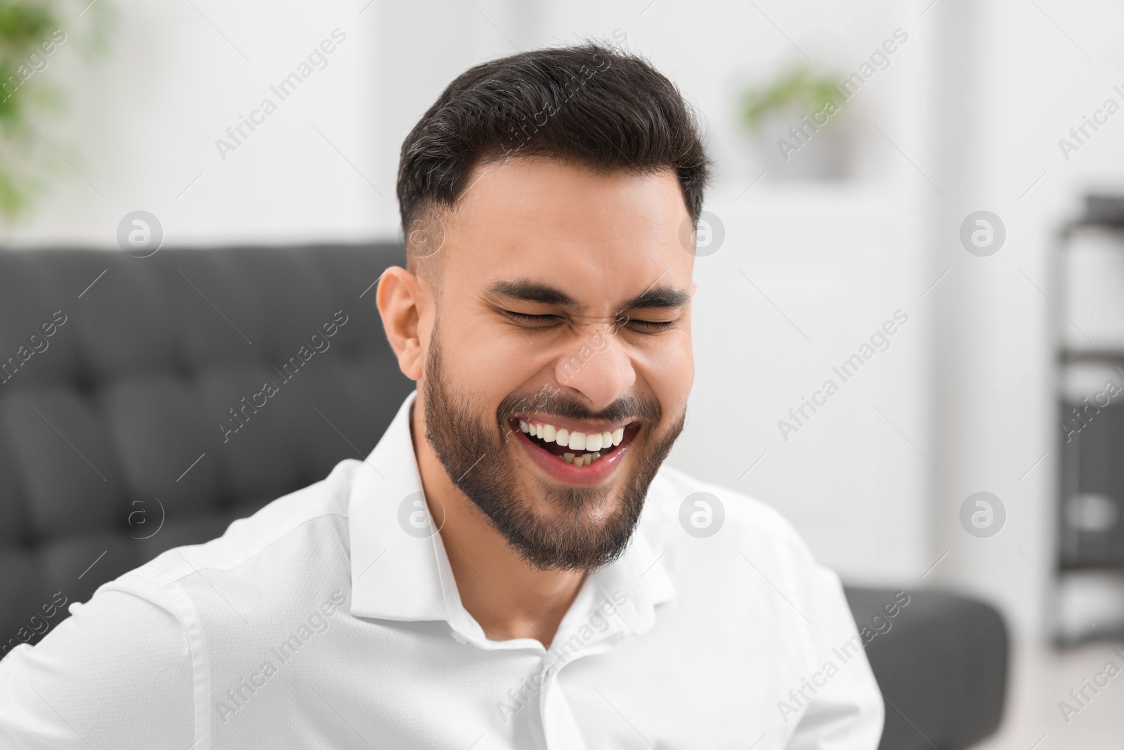 Photo of Portrait of handsome young man laughing in office