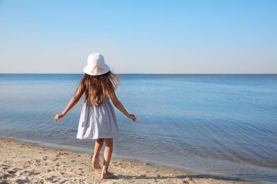 Photo of Cute little child running at sandy beach on sunny day