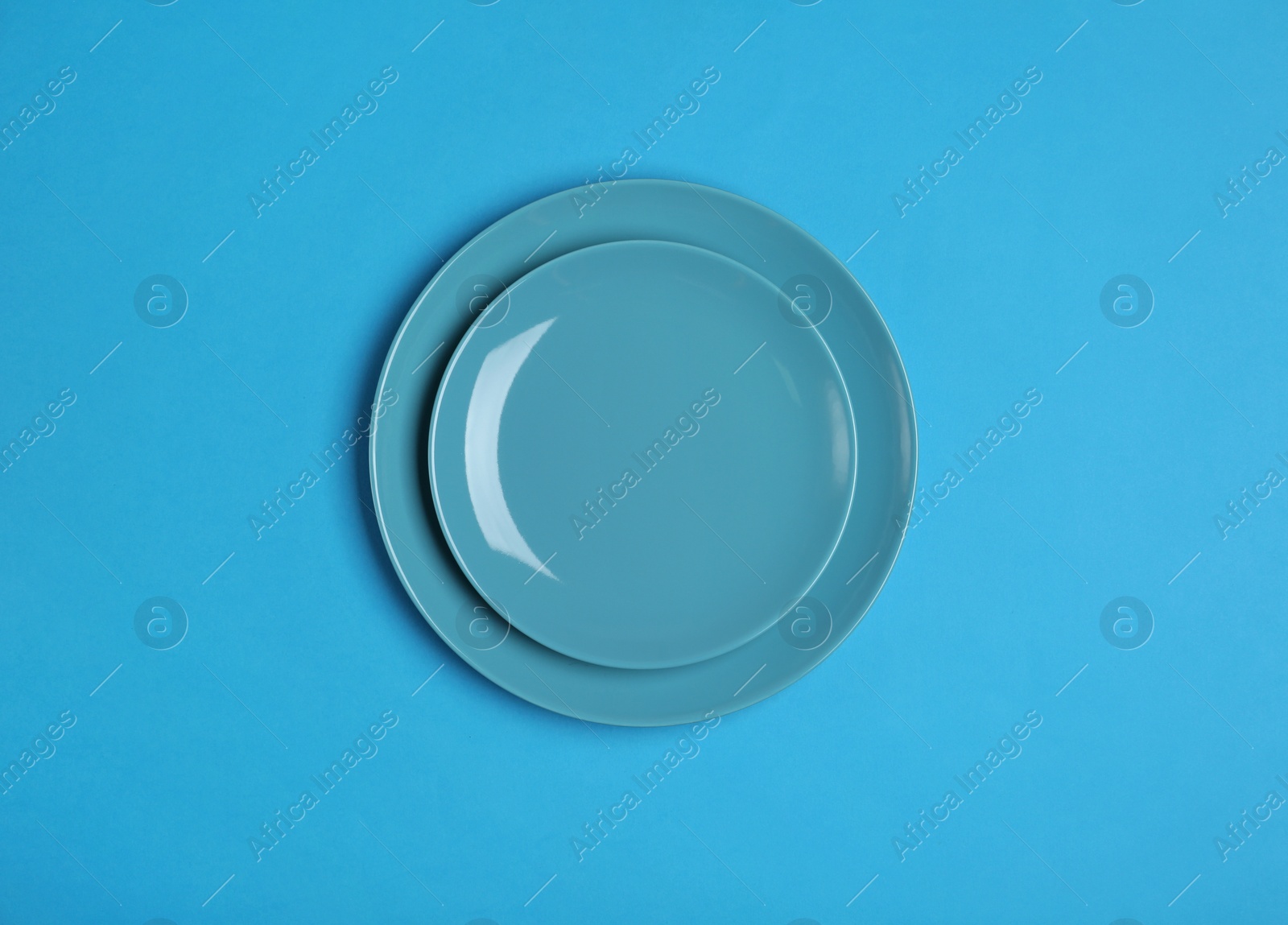 Photo of Clean empty plates on blue background, top view