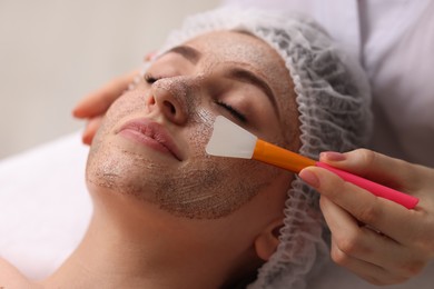 Photo of Cosmetologist applying mask on woman's face in clinic, closeup