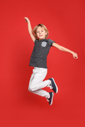 Photo of Cute little boy jumping on red background
