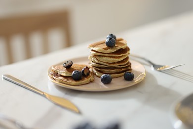 Tasty breakfast. Fresh pancakes with blueberries served on white table, selective focus
