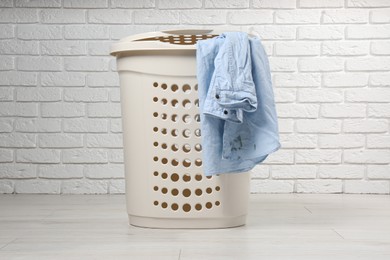 Photo of Laundry basket with clothes near white brick wall