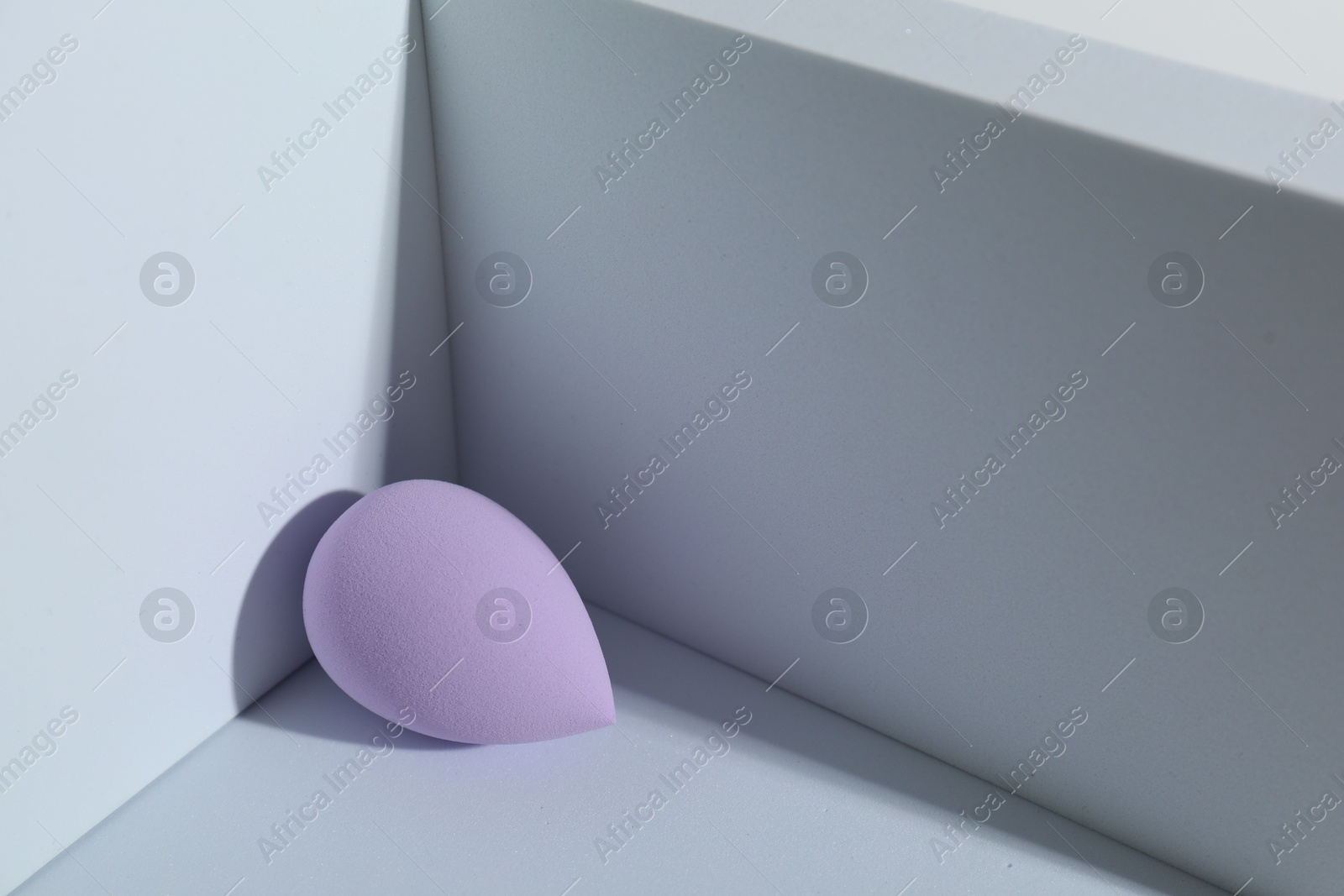 Photo of One violet makeup sponge on light background