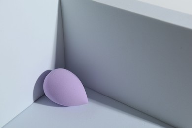 One violet makeup sponge on light background