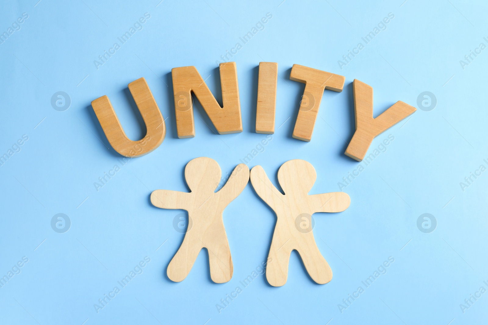 Photo of Wooden people giving high five and word UNITY on color background. Unity concept