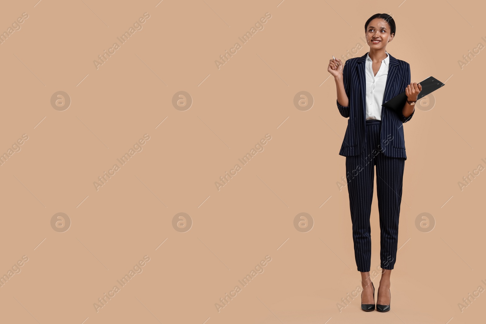 Photo of Beautiful secretary with clipboard and pen on beige background, space for text