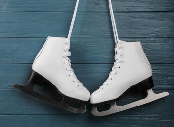 Photo of Pair of white ice skates hanging on blue wooden background