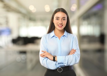 Image of Portrait of happy woman in office. Pretty girl looking at camera and smiling on blurred background